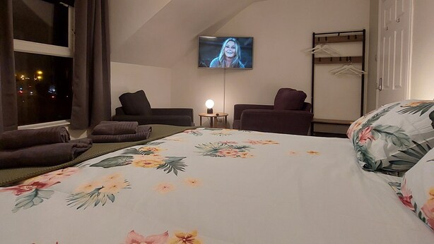 A hotel room with a bed, two chairs, a TV, and a wardrobe. - Woodstock Townhouse Belfast (Belfast)