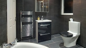 A modern bathroom with a bathtub, a toilet, a sink, and a mirror. - Woodstock Townhouse Belfast (Belfast)