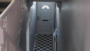 A narrow hallway with a checkered floor leading to a door with a semi-circular window. - Woodstock Townhouse Belfast (Belfast)
