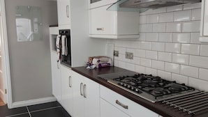 A modern kitchen with white cabinets, a gas stove, and a glass range hood. - Woodstock Townhouse Belfast (Belfast)