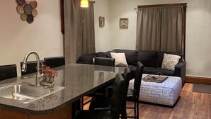Cocina moderna con encimera de granito, pileta de acero inoxidable e iluminación colgante.