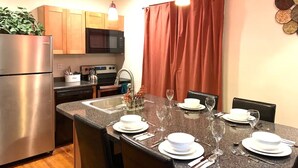Cocina moderna con encimeras de granito, electrodomésticos de acero inoxidable y comedor para seis personas.
