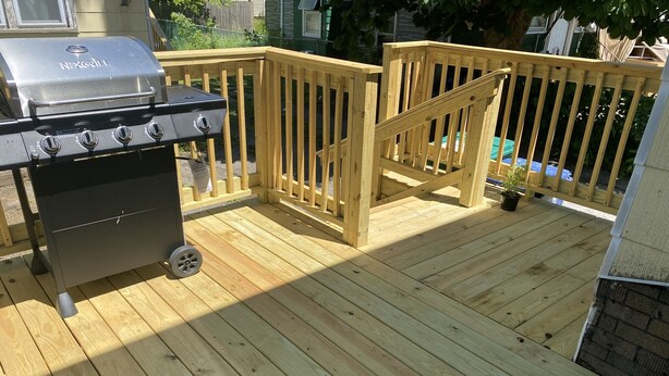 Una terraza de madera con una parrilla.