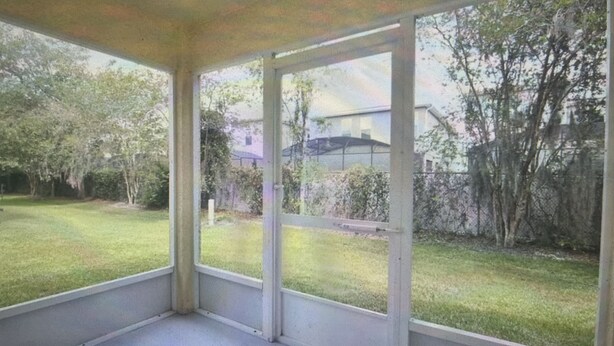 A covered outdoor area with a view of a grassy yard and trees.