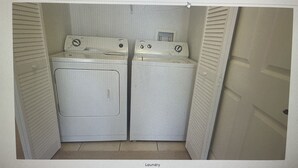 A laundry room with two washing machines and a dryer.