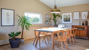 Un comedor con una mesa y sillas de madera, una lámpara colgante y cuadros en las paredes.