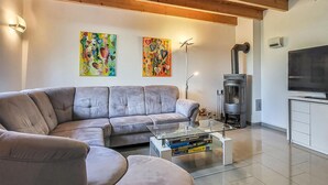 Un soggiorno moderno con un divano grigio, un tavolino in vetro, un caminetto e due quadri colorati appesi alla parete.