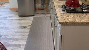 A compact kitchen with a stainless steel refrigerator, a small wooden table, a gas stove, and a built-in oven. - The Loft at Reverie Gardens (Sequim)