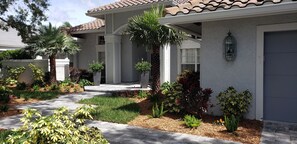 Stroll through the beautifully maintained garden, featuring a variety of plants and shrubs, to the inviting entrance.