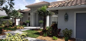 Stucco exterior and terracotta roof tiles adorn this charming home, complete with a covered porch and lush landscaping.