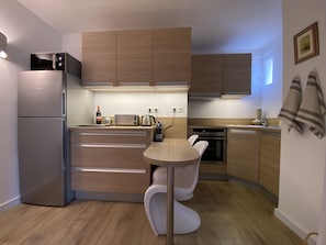 Een koelkast, een kookplaat, een waterkoker, kookgerei, borden en bestek