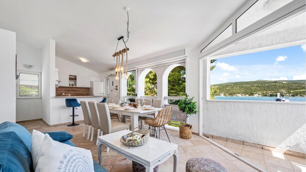 Amplia sala de estar con una mesa de comedor, sofás y vista al mar.