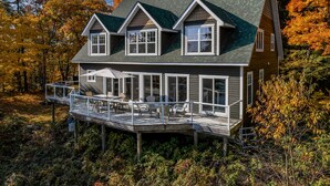 A two-story house with a deck, large windows, and a steep roof.