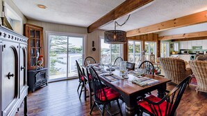 A dining area with a wooden table, chairs, and a view of a lake through large windows.