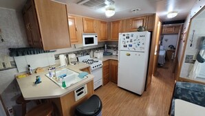 A compact kitchen with wooden cabinets, a microwave, a refrigerator, a stove, and a sink. - Key Largo Relaxing Gataway with Stoning Sunsets Views (Key Largo)