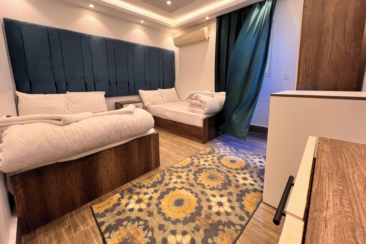 Een hotelkamer met twee bedden, een kamerbreed tapijt met dessin en een modern hoofdeinde.