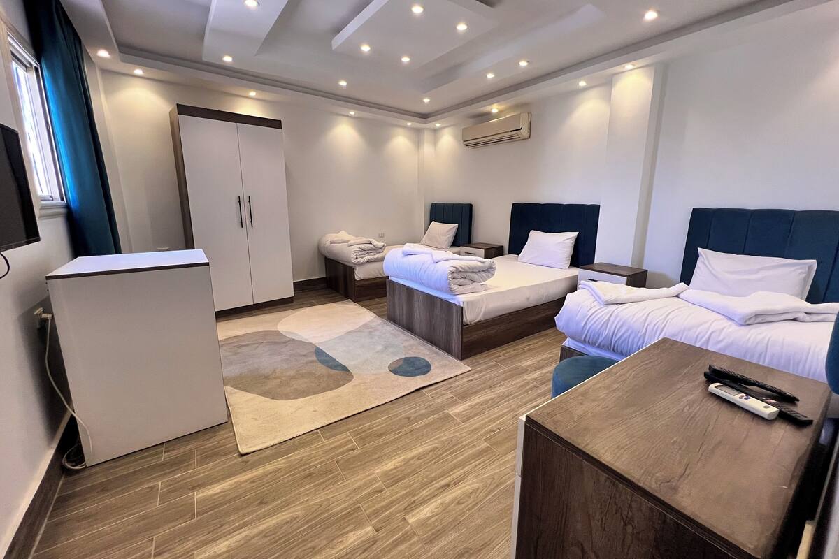 Een moderne hotelkamer met een bed, nachtkastjes, een bureau, een kledingkast en een airconditioning.