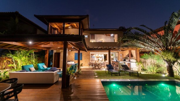 A modern house with a pool, outdoor seating, and a covered patio area.