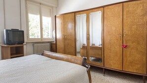 Et soveværelse med seng, garderobe og fjernsyn.