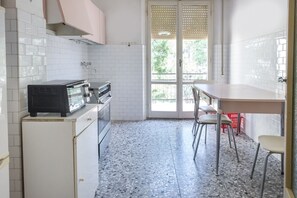 Una cocina con armarios blancos, un microondas y un comedor con sillas.
