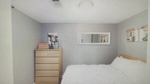Een slaapkamer met een bed, een dressoir en een tafeltje met een fotolijstje.