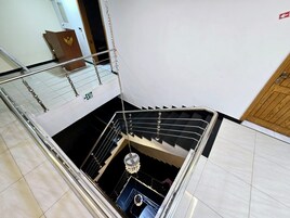 Un interior de varios niveles con una escalera, una araña y una puerta con panel de madera.
