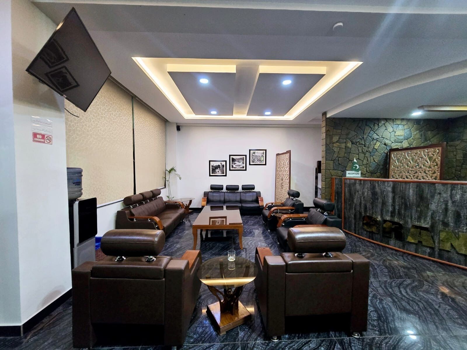 A reception area with a stone wall, a reception desk, and a seating area with leather sofas and armchairs.