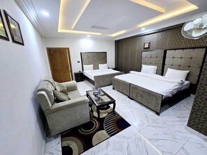 Une chambre d’hôtel moderne avec un grand lit, un canapé, une petite table et un ventilateur de plafond.