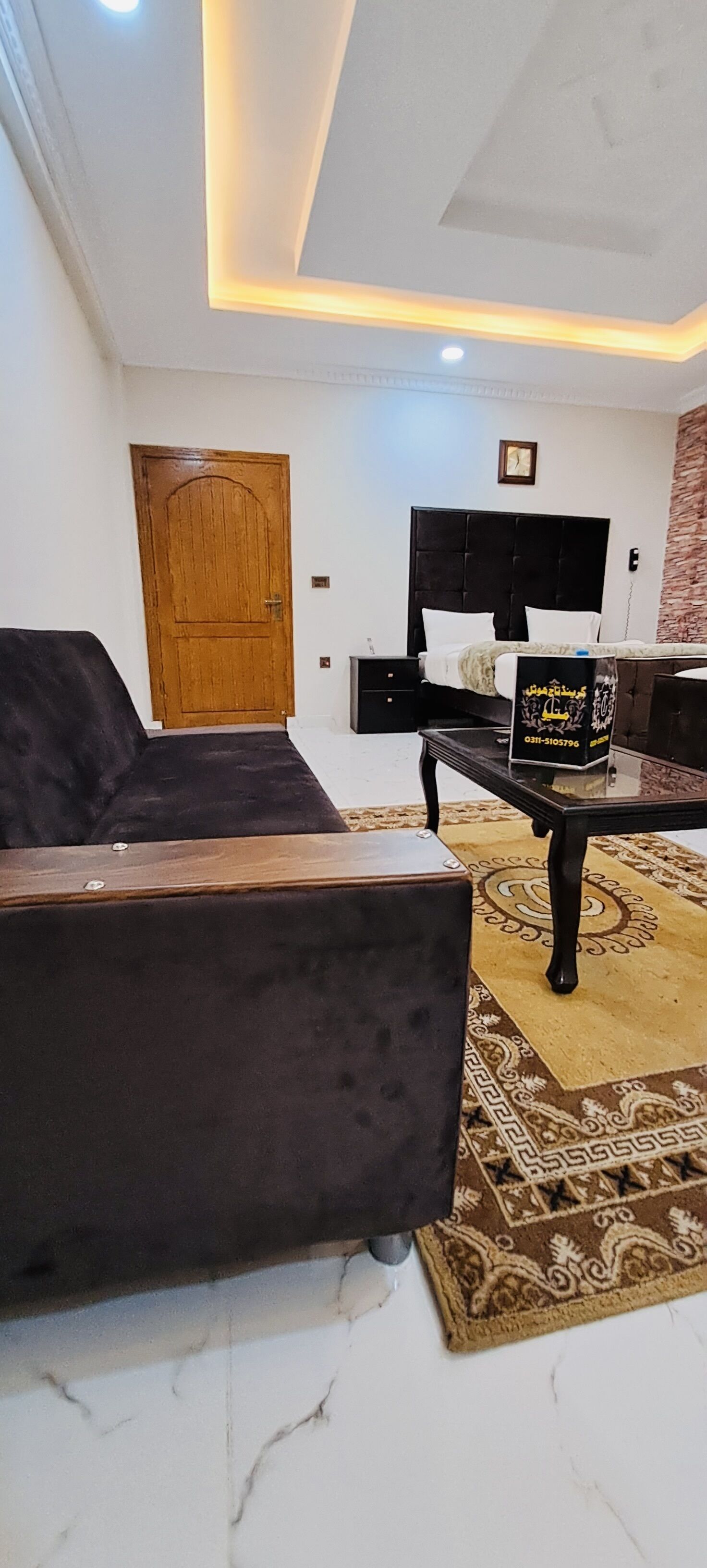 A modern living room with a dark sofa, a coffee table, and a patterned rug.