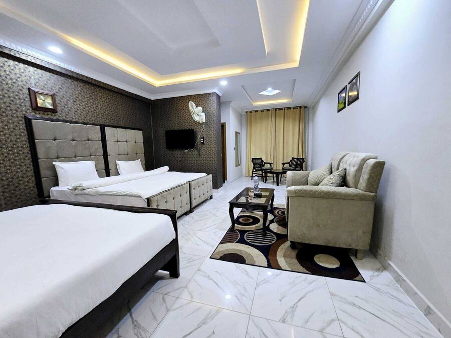 Una habitación de hotel moderna con una cama grande, un sofá, una mesita y un televisor.