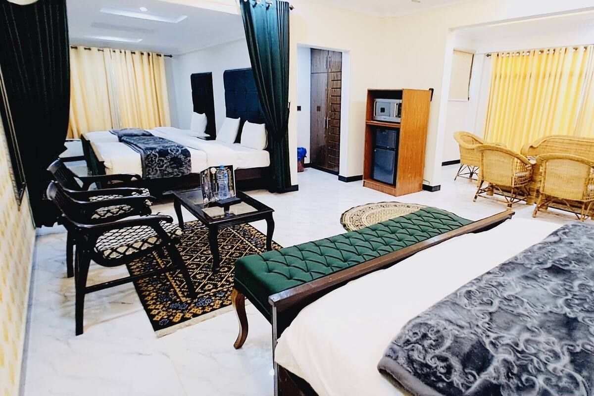 Ein Hotelzimmer mit Bett, Schreibtisch, Stuhl, einem kleinen Tisch, einer Bank und einem Kleiderschrank.