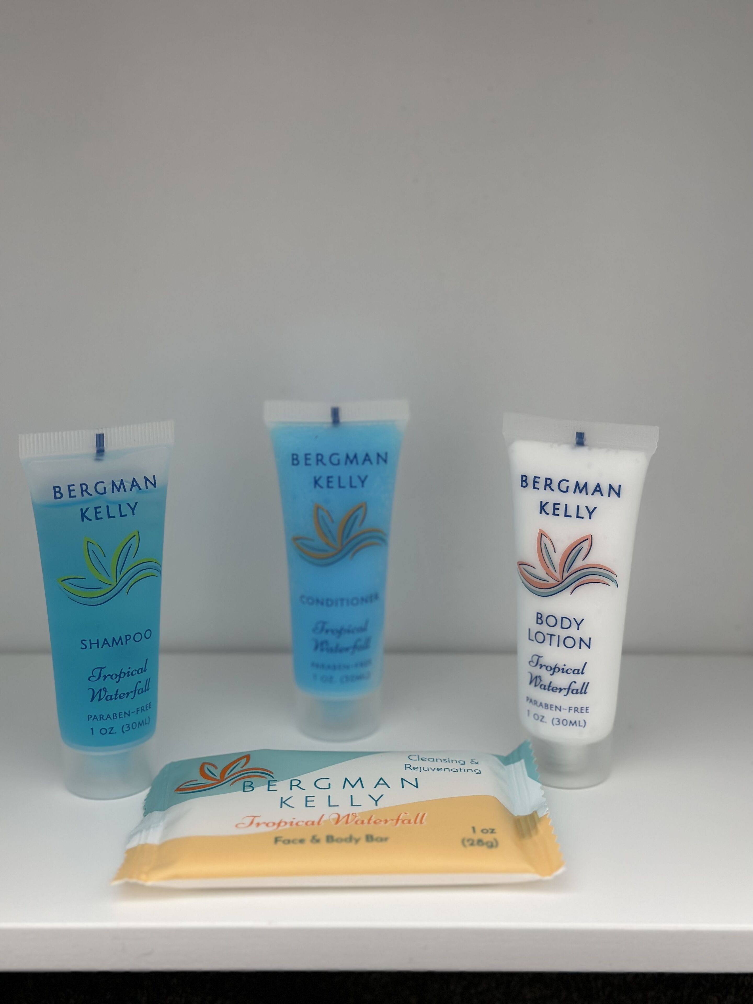 Trois produits de la marque Bergman Kelly : un shampooing, un après-shampooing et une lotion pour le corps, tous à la fragrance « Tropical Waterfall », ainsi qu’un savon pour le visage et le corps, également à la fragrance « Tropical Waterfall ».