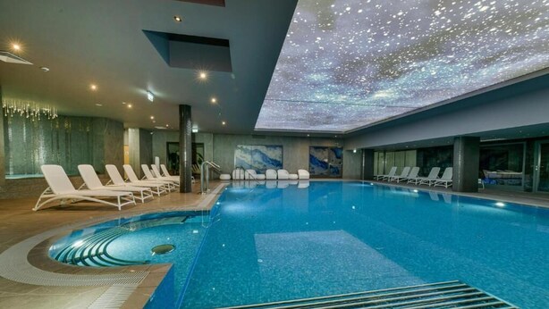 A modern indoor swimming pool with a starry sky ceiling, lounge chairs, and a clear view of the pool. - Factory Resort Wellness & SPA (Kolobrzeg)