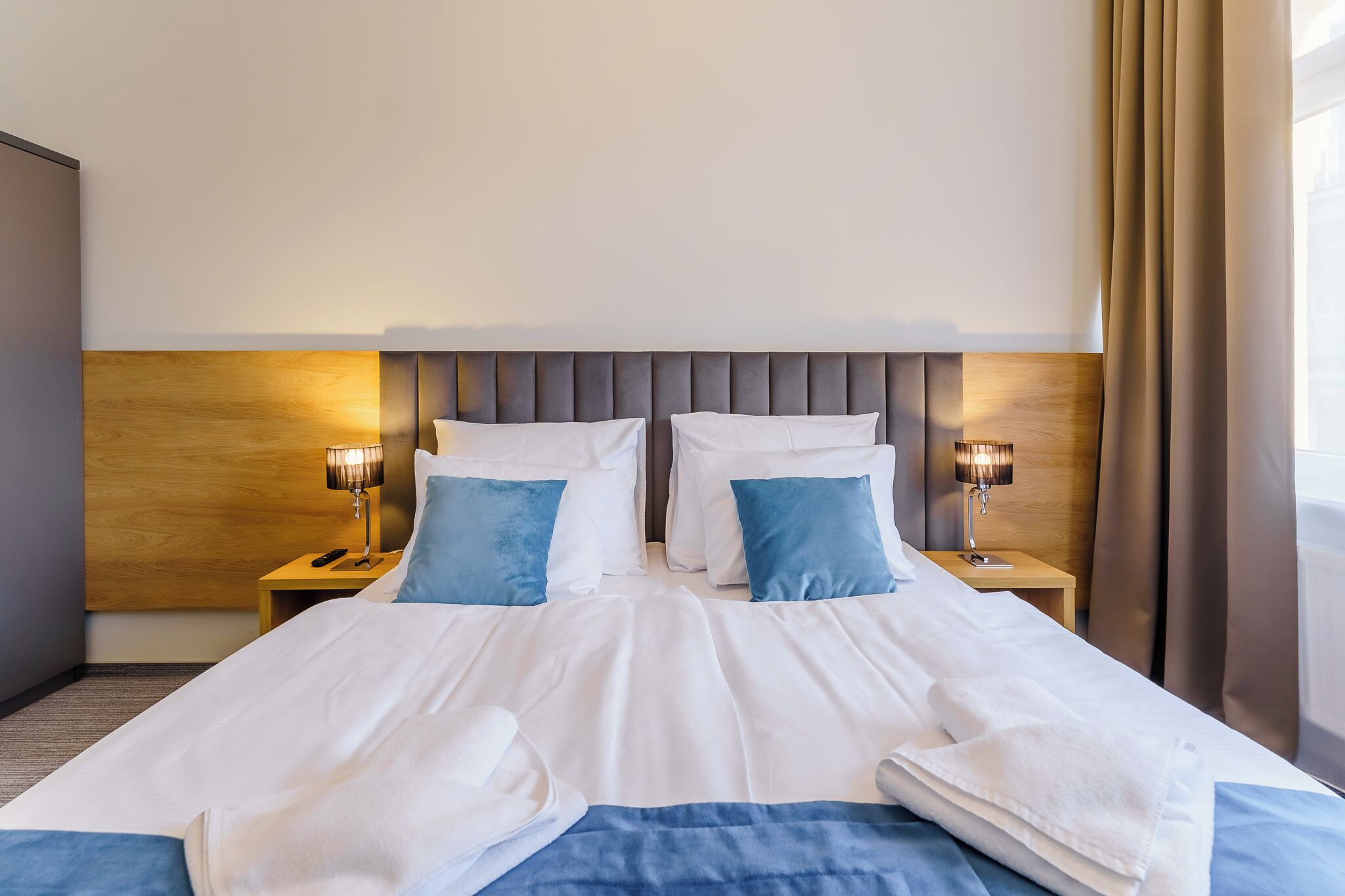 Ein Hotelzimmer mit einem großen Bett, zwei Nachttischen und einem Kopfteil mit einer Holzvertäfelung.