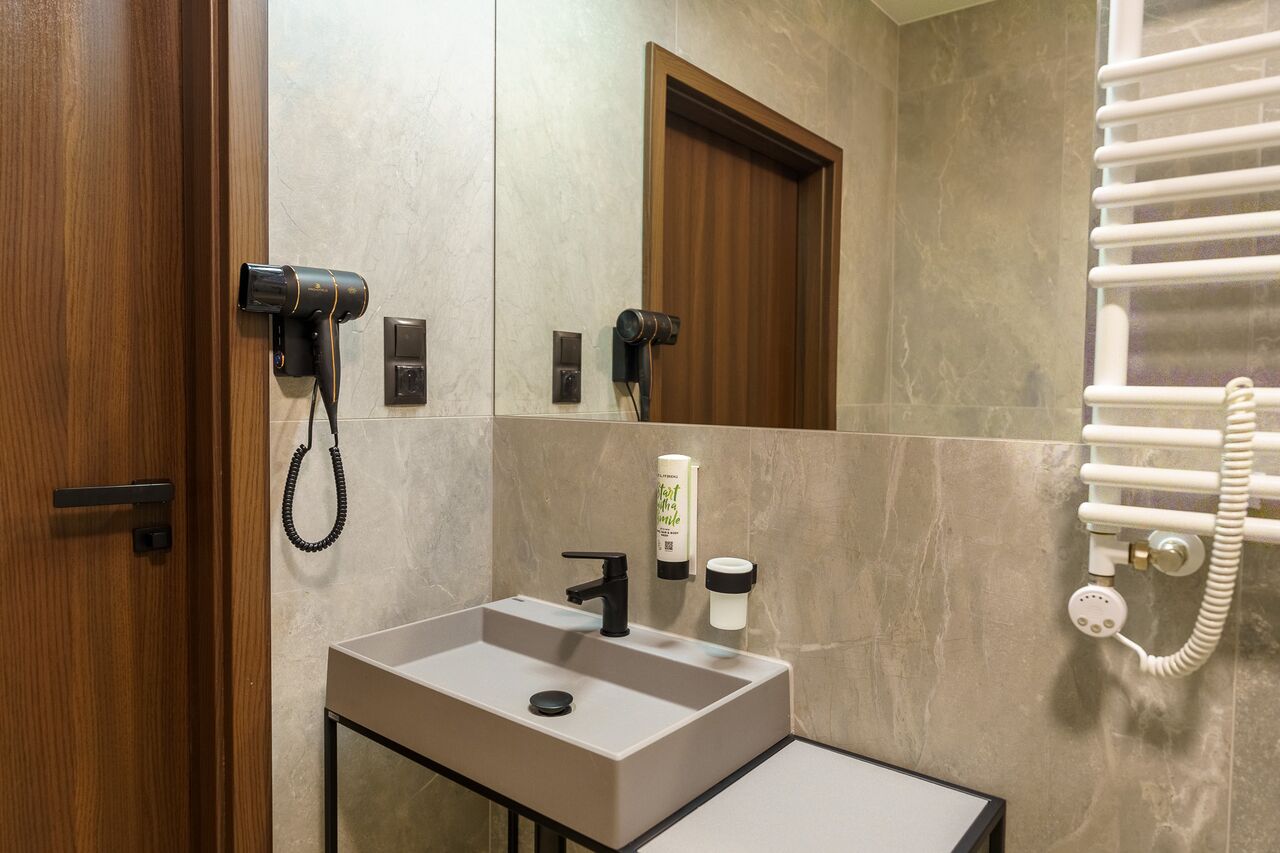 A modern bathroom with a sink, a hairdryer, and a towel rack.
