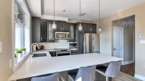 A modern kitchen with dark cabinets, stainless steel appliances, and a large island with bar stools. - Luxury 2 bedroom, 2 bath condo , 2 balconies, hi speed WIFI with FREE parking (Montréal)