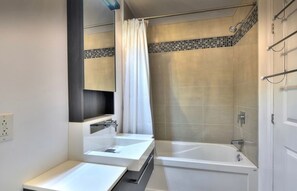 Ein modernes Badezimmer mit zwei Waschbecken, einer Badewanne und einer Dusche.