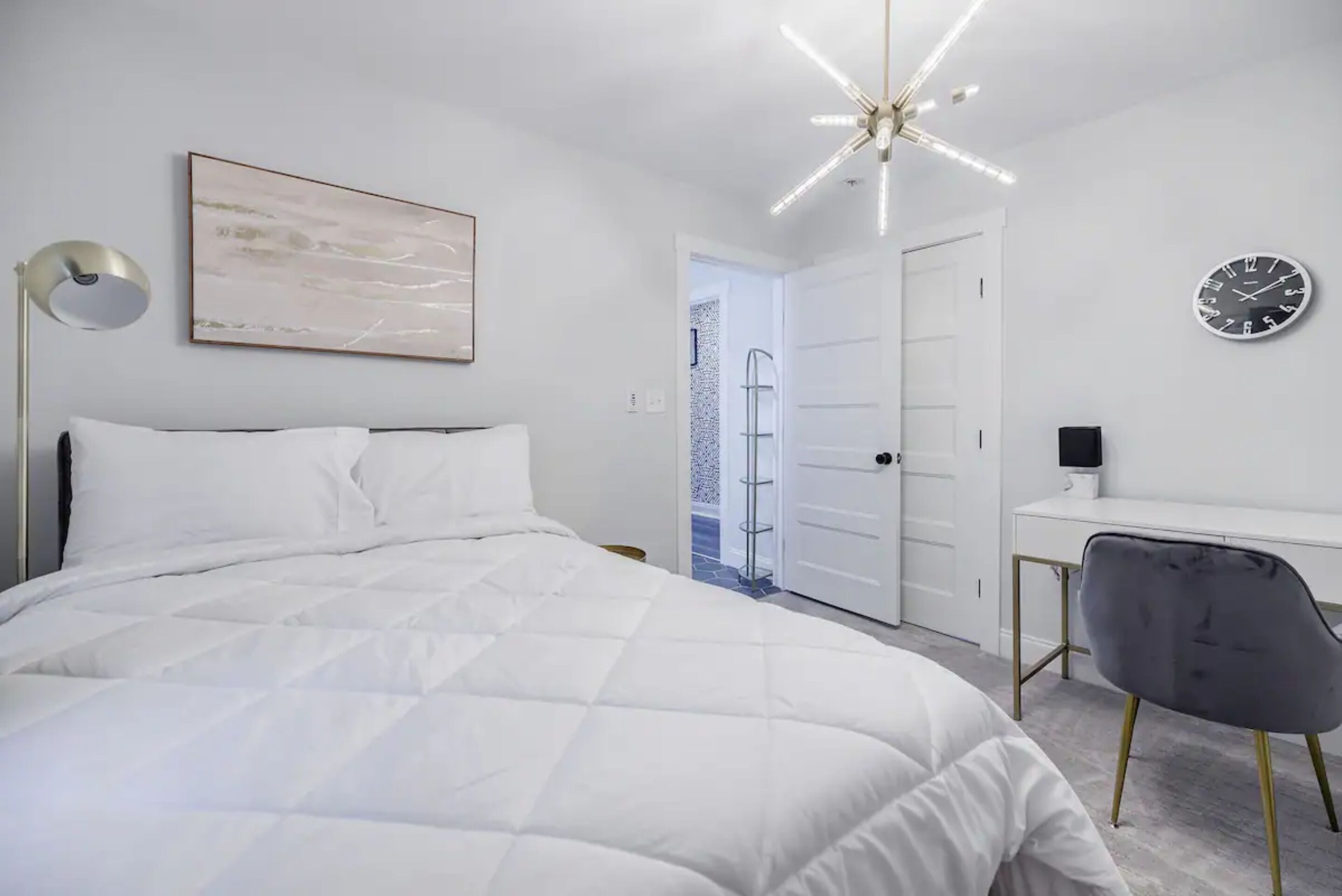 A modern bedroom with a large bed, a desk, and a chair.