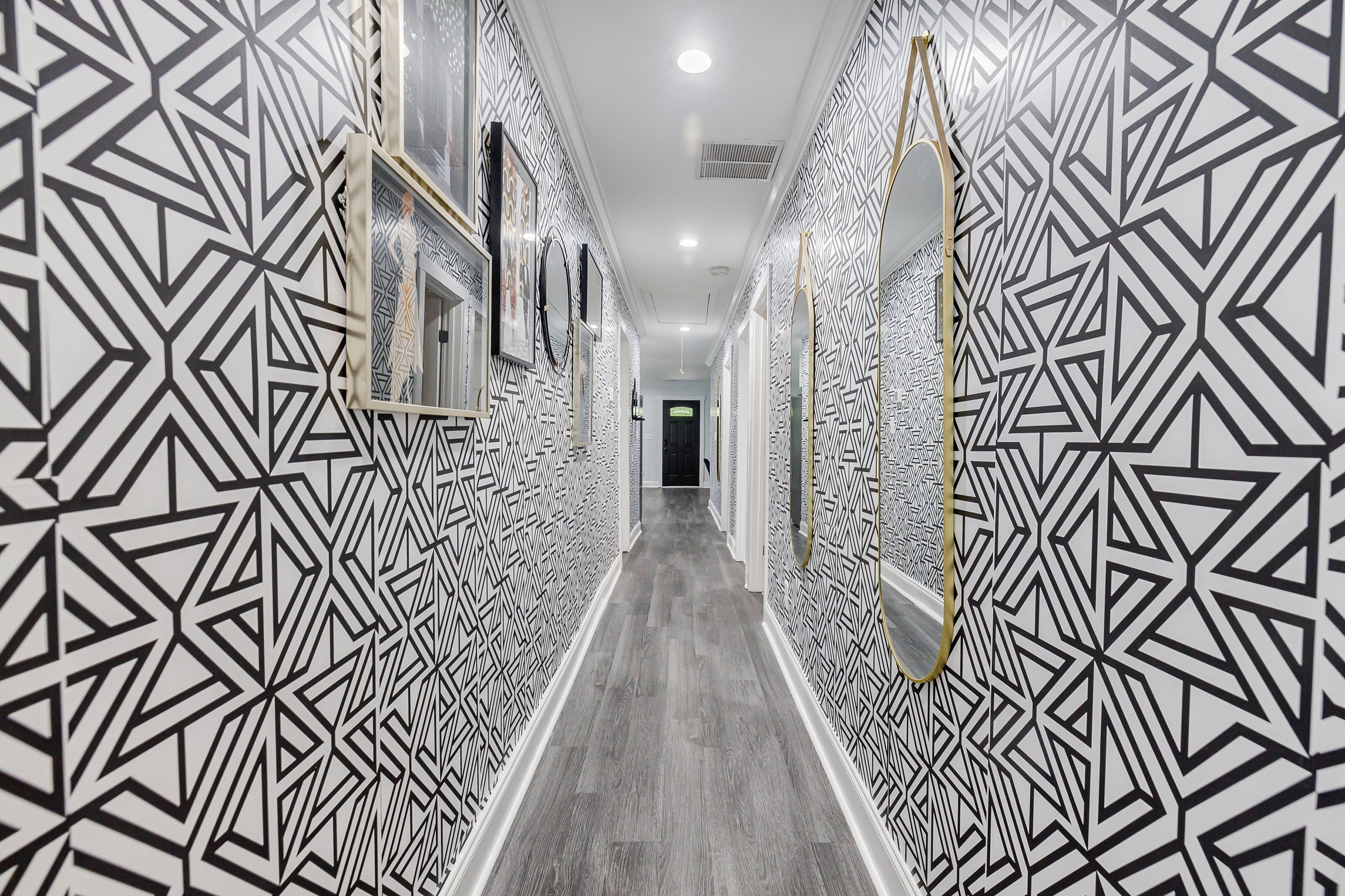 A hallway with geometric patterned walls and a wooden floor.