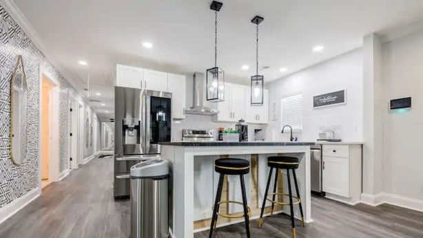 A modern kitchen with white cabinetry, stainless steel appliances, and a central island with bar stools. - Atlanta's Hidden Gem: Modern 4BR/2BA House with Grill and Outdoor Space! (Atlanta)