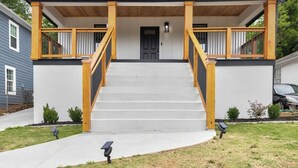 A two-story house with a front porch, a staircase, and a door. - Atlanta's Hidden Gem: Modern 4BR/2BA House with Grill and Outdoor Space! (Atlanta)
