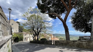 A stone-paved street with a view of a town and distant hills. - Tina's House (Cortona)