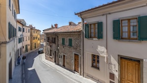 A narrow street lined with historic buildings, featuring stone facades and traditional wooden shutters. - Tina's House (Cortona)