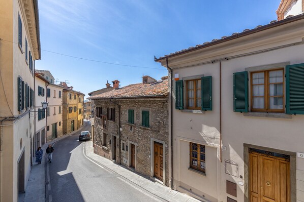 A narrow street lined with historic buildings, featuring stone facades and traditional wooden shutters.