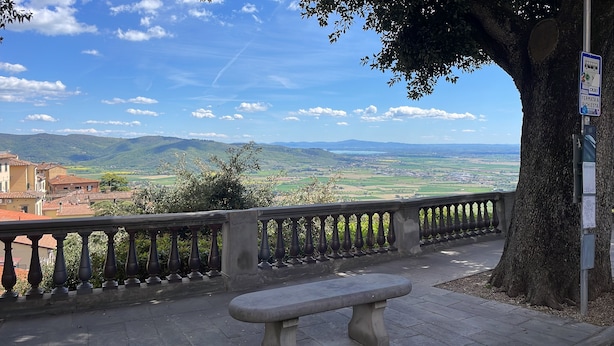 A bench overlooking a scenic view of a town with a tree and a signpost. - Tina's House (Cortona)