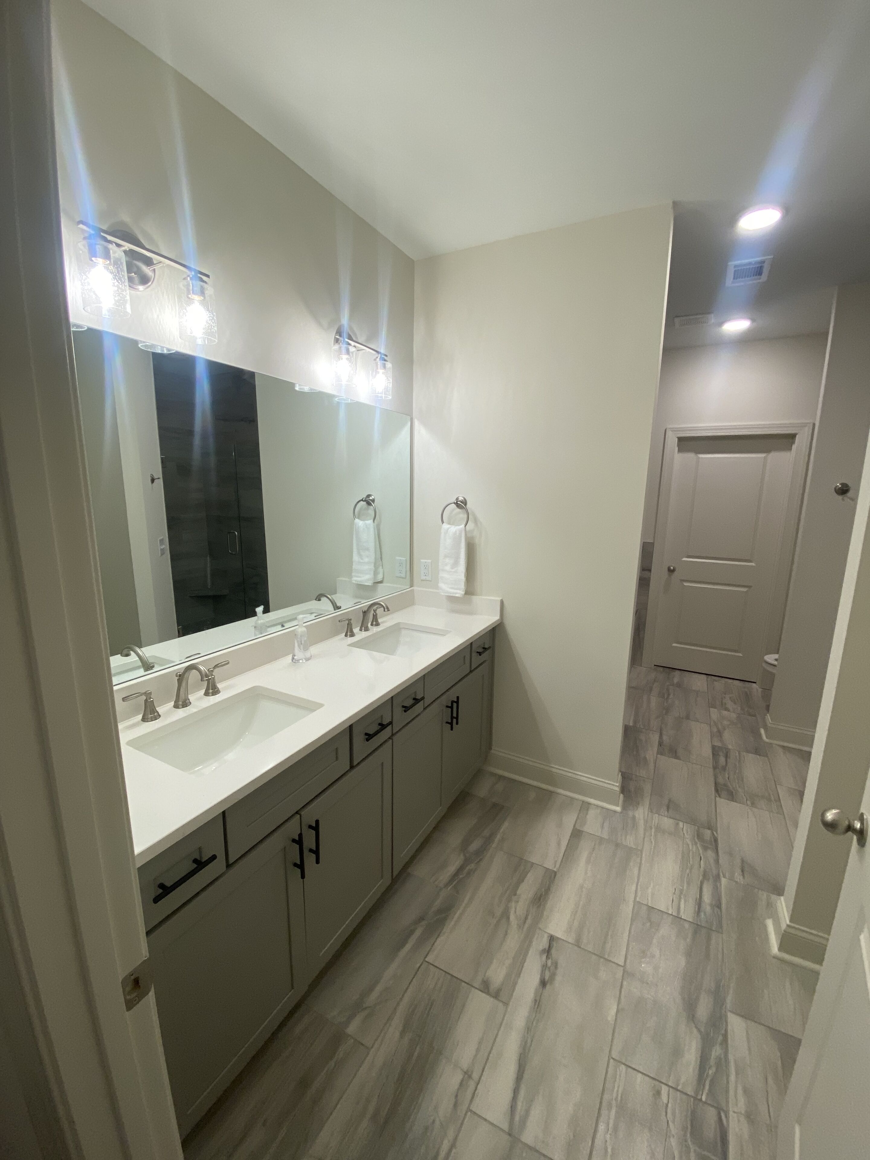 Une salle de bain moderne avec un grand miroir, deux lavabos et un dressing.