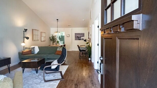 Un salon spacieux avec un canapé vert, une table basse et un coin repas comprenant une table et des chaises.