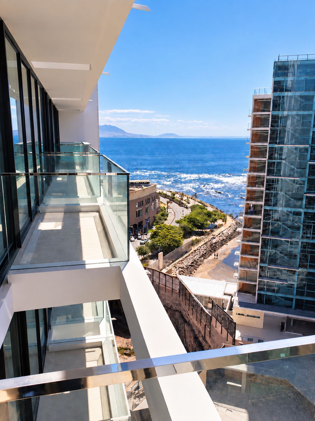 Un edificio de gran altura con un balcón de vidrio que domina una zona costera.