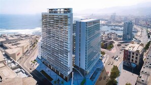 Un edificio de gran altura con varios pisos, una terraza en la azotea y vistas al océano.