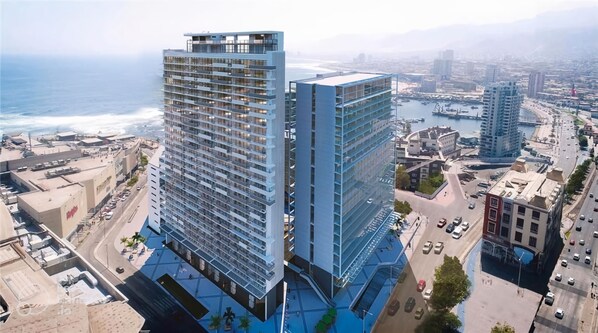 A high-rise building with multiple floors, a rooftop terrace, and a view of the ocean.
